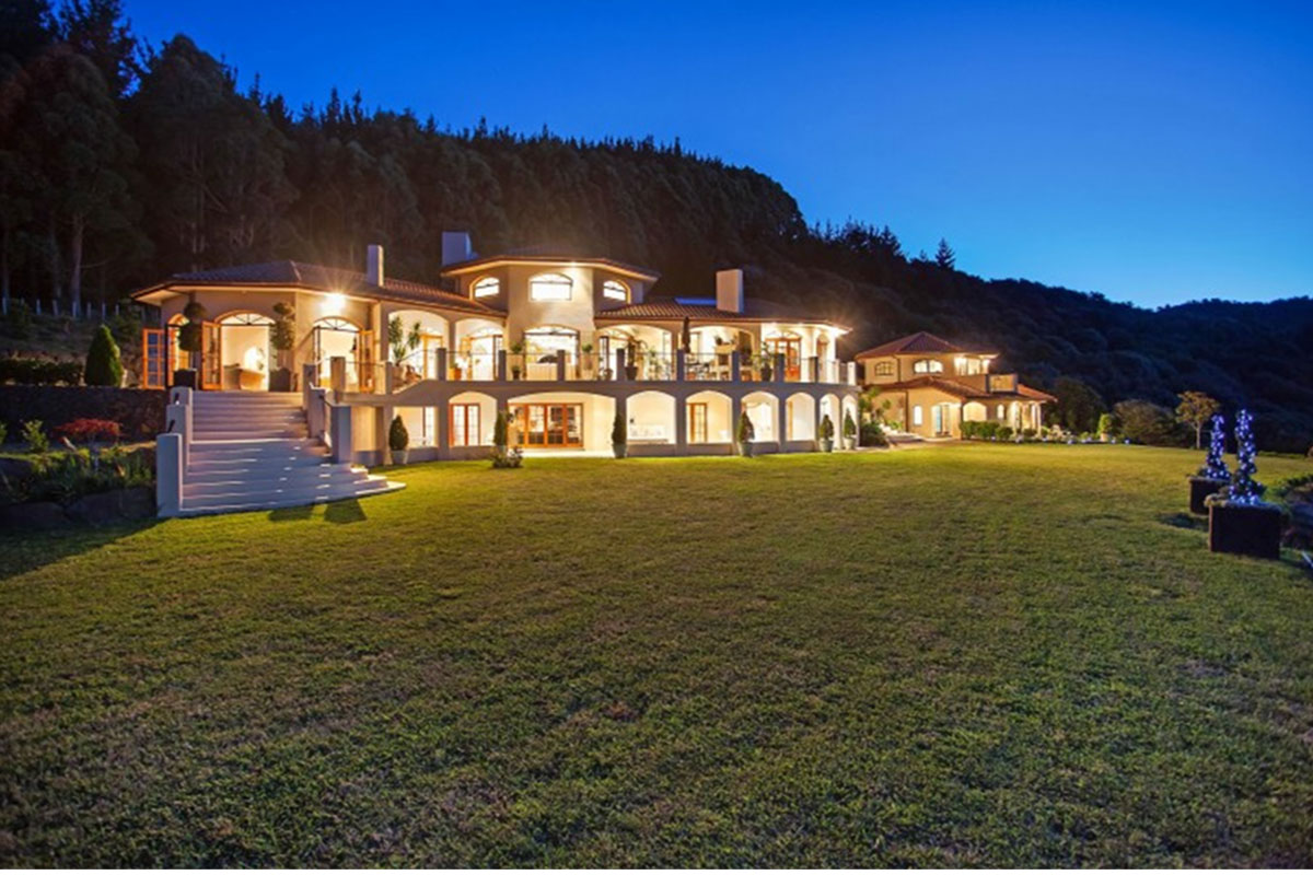Mediterranean-style two-storey venue lit at night with arched colonnades against dark hills