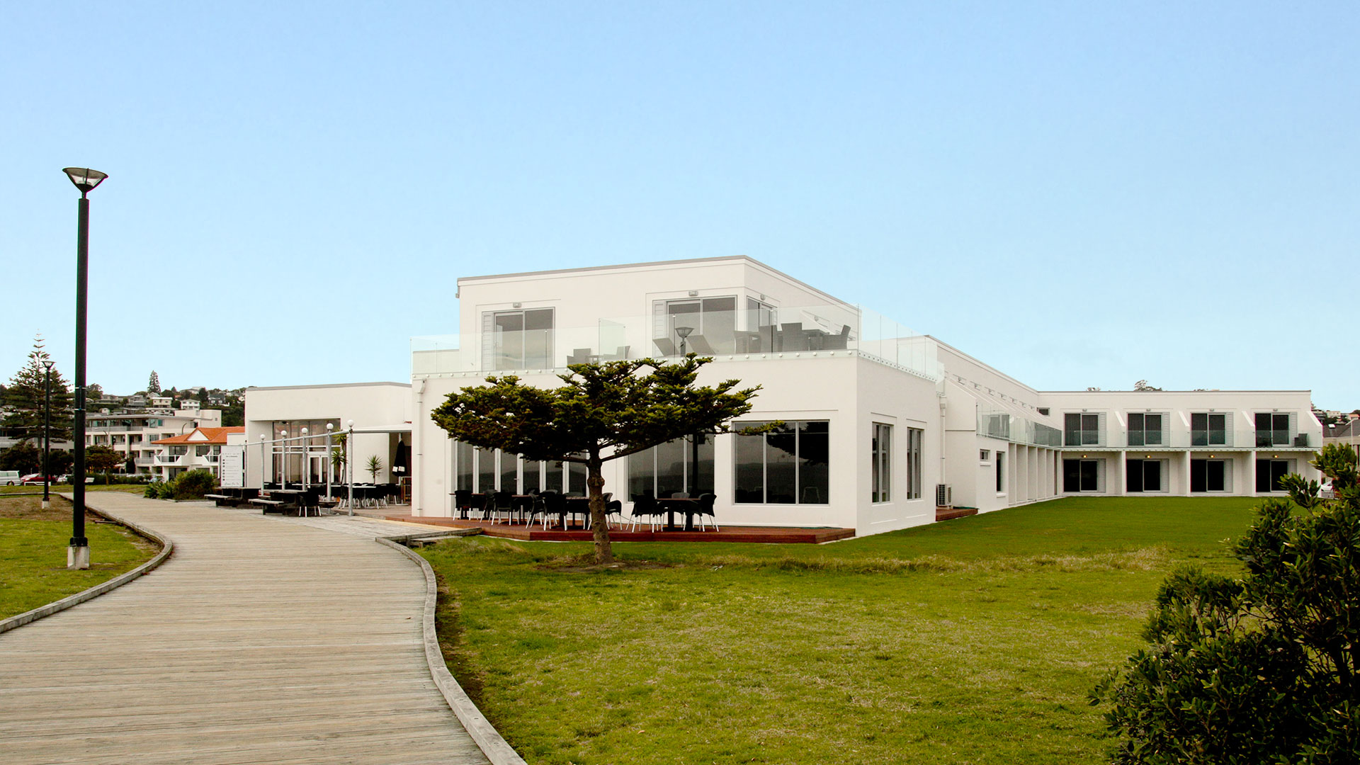 White hotel building exterior with lawn and boardwalk approach