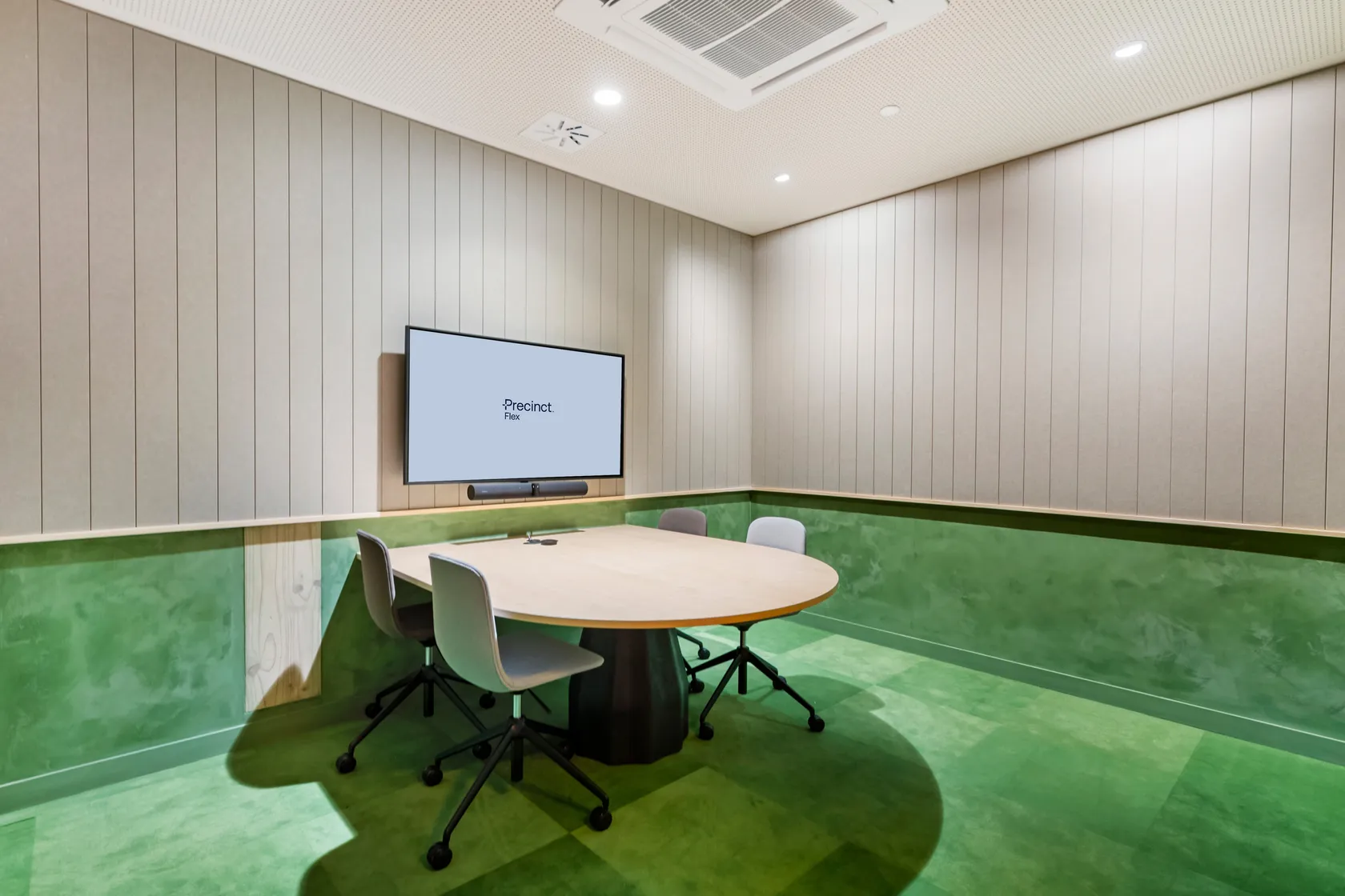 Small meeting room with round-ended table, grey chairs, screen and vertical timber wall panelling
