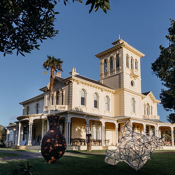 Large cream Victorian Italianate homestead with tower, wide verandah and columns, sculptures on lawn