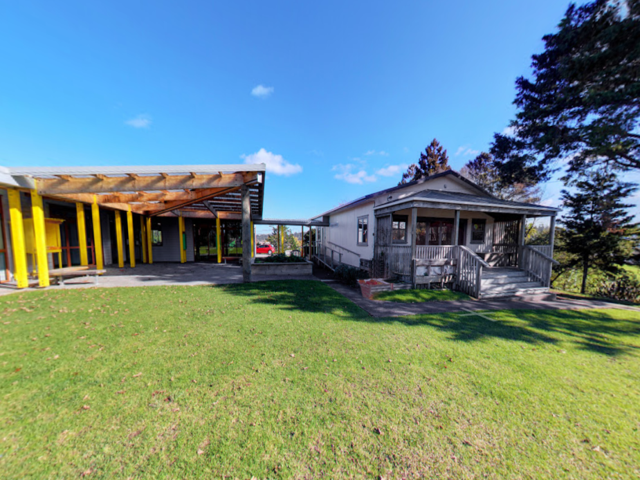 Community hub exterior showing modern block and older weatherboard cottage with lawn