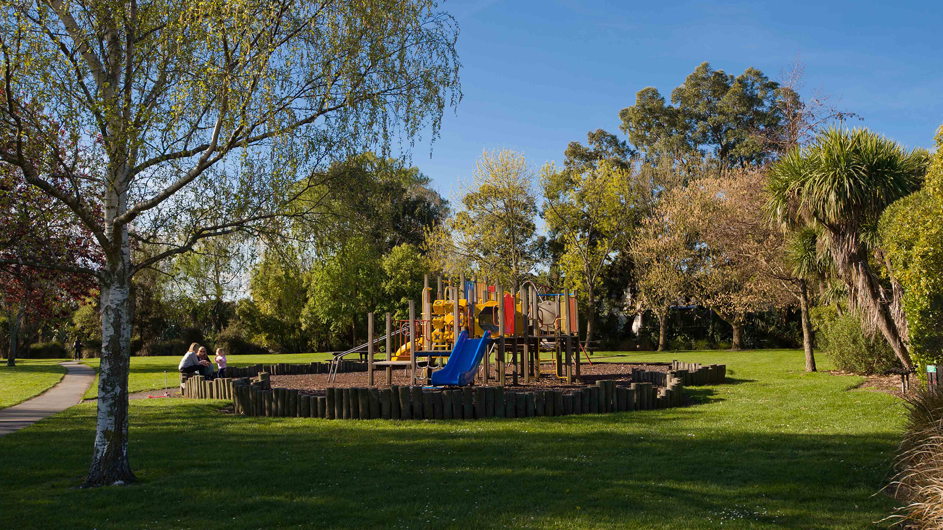 Playground with colourful equipment on a grass park with trees