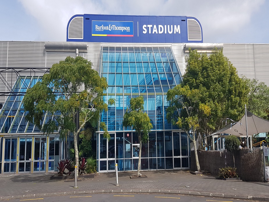 Stadium building facade with large glazed entrance and branded signage above