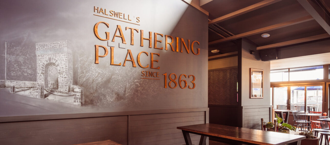 Pub bar area with branded mural wall, timber tables and booth seating