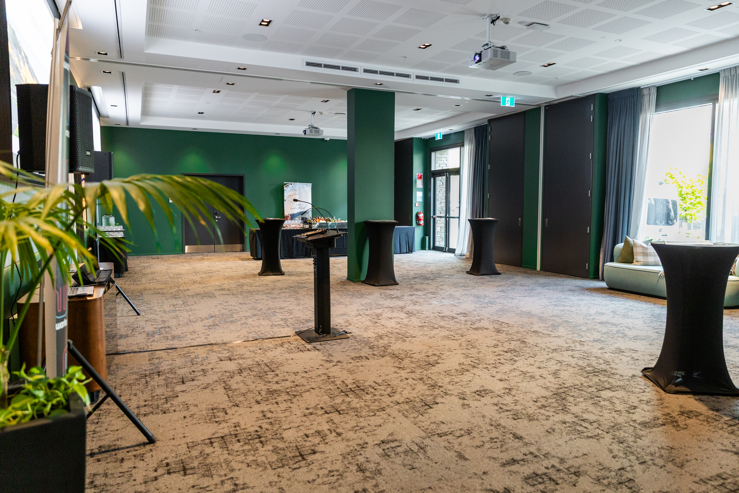 Large event space with green accent walls, standing tables and folding partition doors