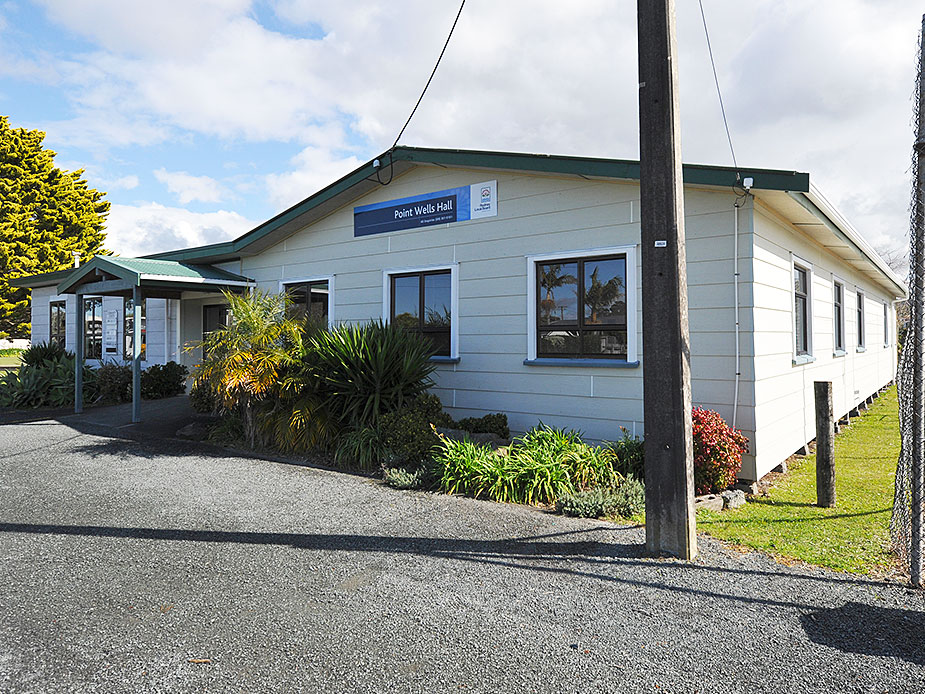 White weatherboard hall exterior from side angle with garden plantings