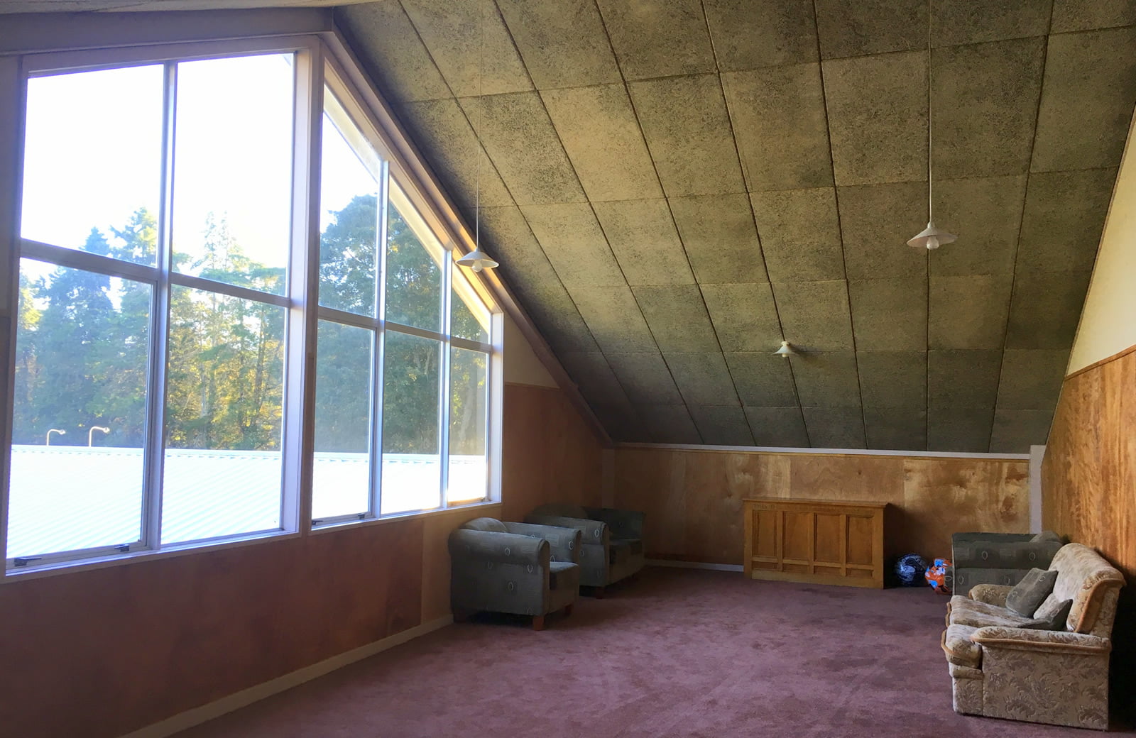 A-frame recreation room with large windows, armchairs and carpeted floor