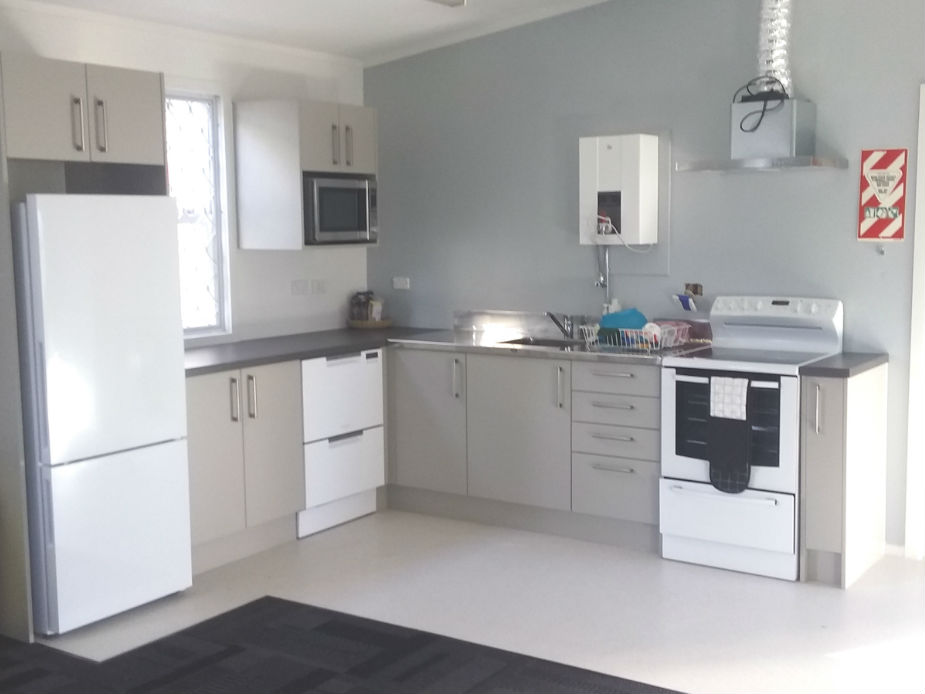 Compact kitchen with white cabinetry, fridge, stove and stainless sink