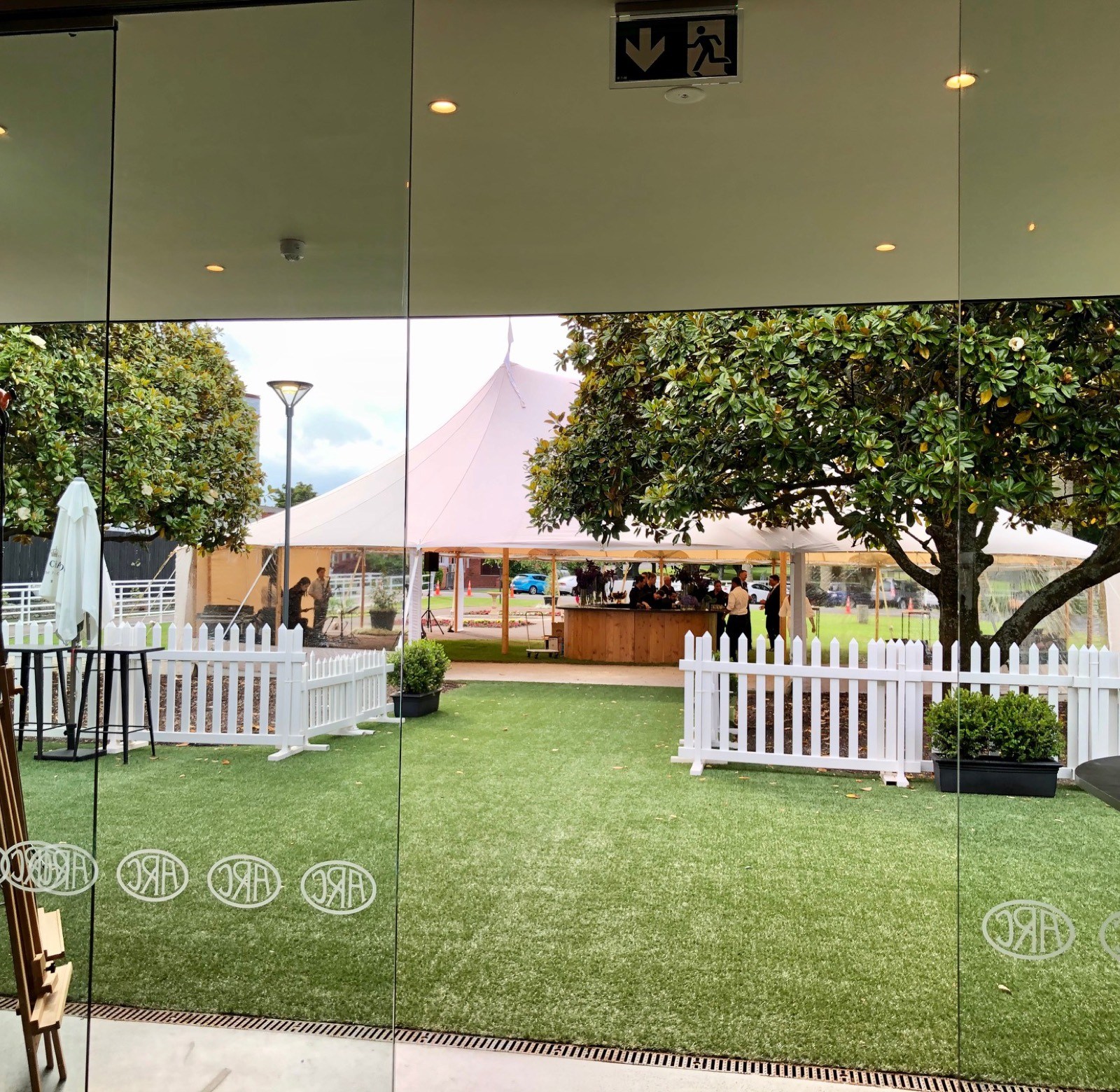 View through glass doors to marquee tent on lawn with trees