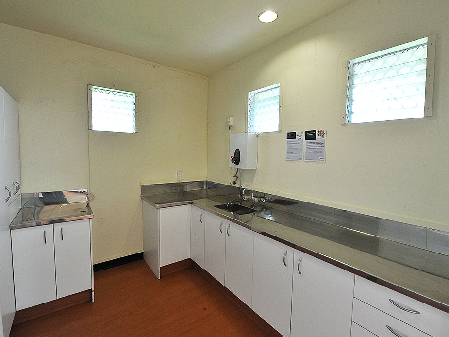 Compact kitchen with stainless benchtops, white cabinetry and louvre windows