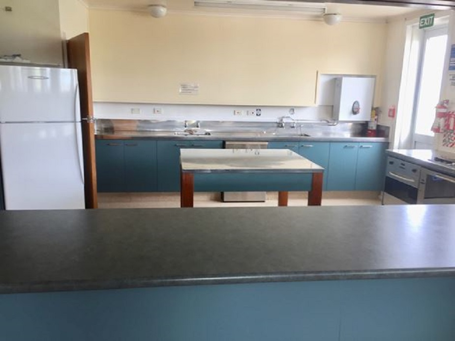 Hall kitchen with teal cabinetry, stainless bench and central island