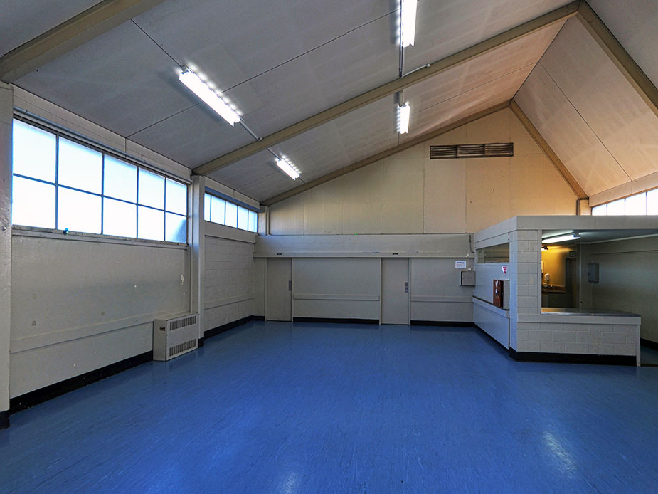 Plain hall interior with blue vinyl floor, angled ceiling and service counter