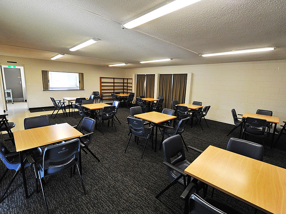 Plain hall room with desks, chairs and drawn curtains