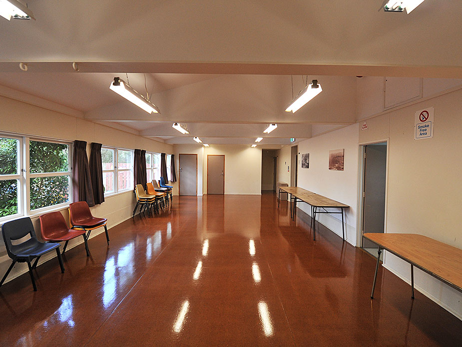 Plain rectangular hall with polished floor, chairs and long trestle table