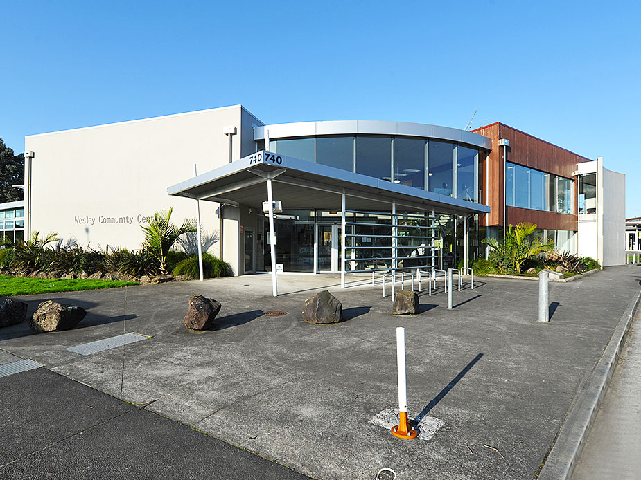 Modern community centre building with curved glazed facade and corten cladding