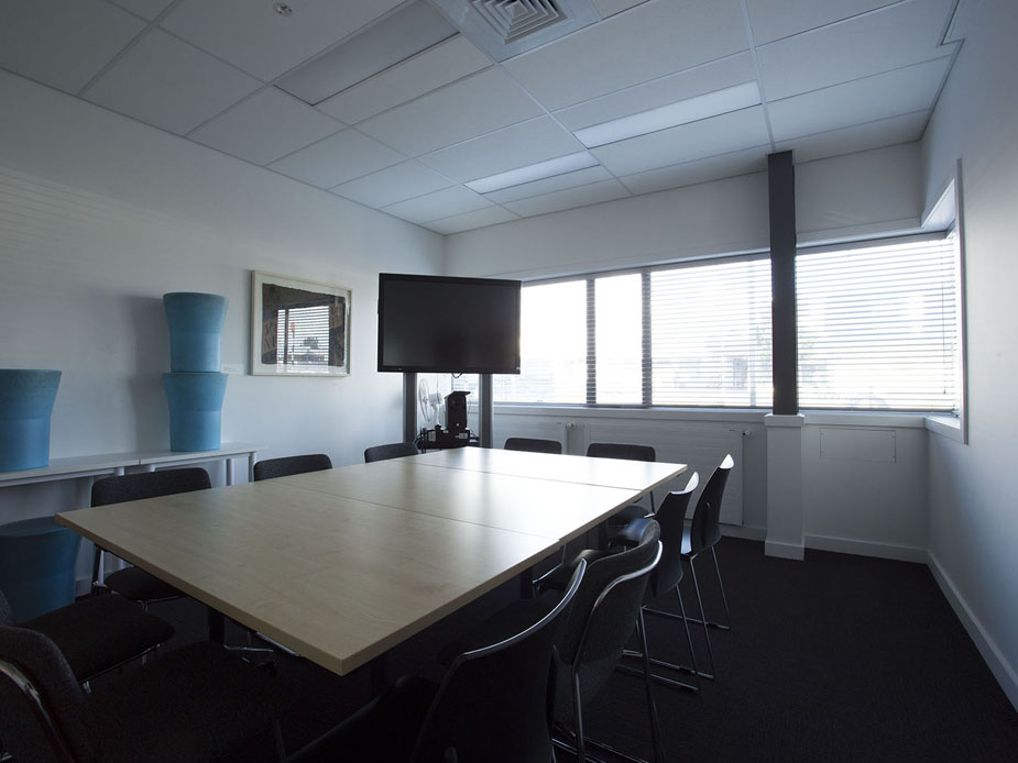 Meeting room with large table, chairs and wall-mounted screen