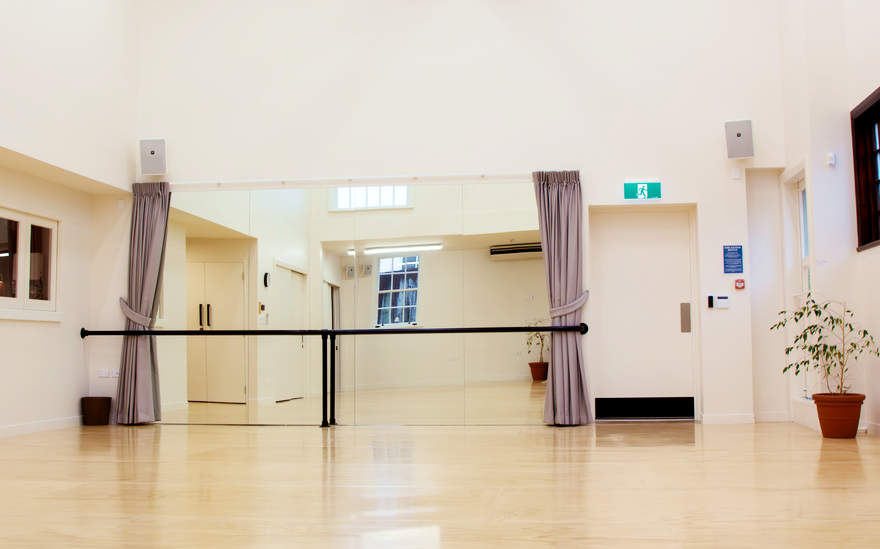 Dance studio with mirrored wall, ballet barre and timber sprung floor