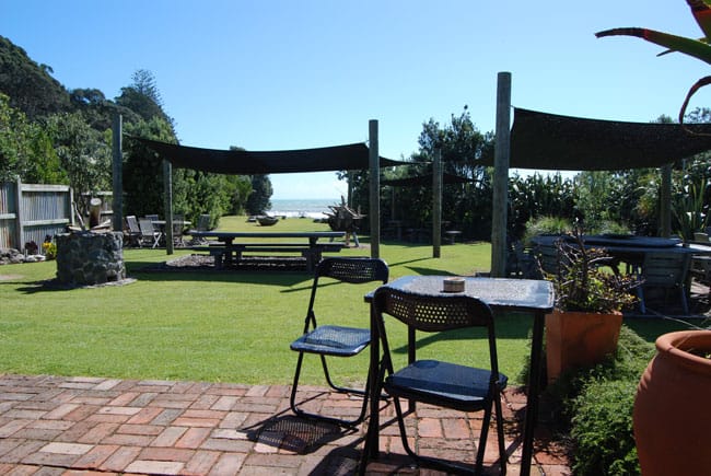 Grassed outdoor event area with shade sails and outdoor furniture, ocean views beyond