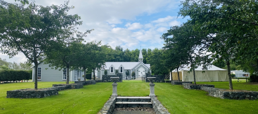 Chapel viewed across garden with stone walls and lawn pathway